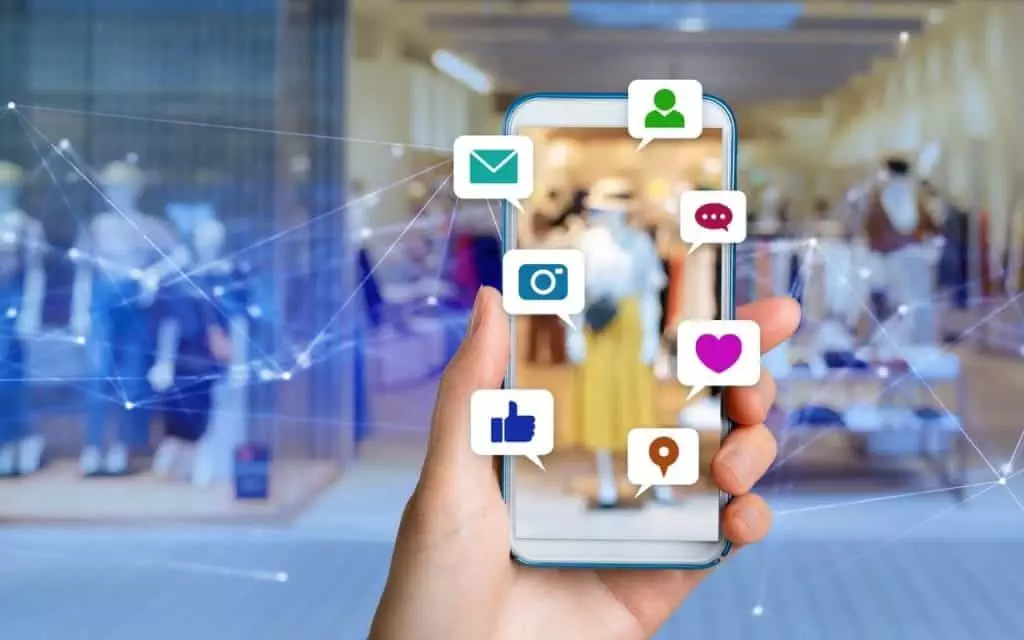 A hand holding a smartphone displaying interactive social icons for direct response marketing.